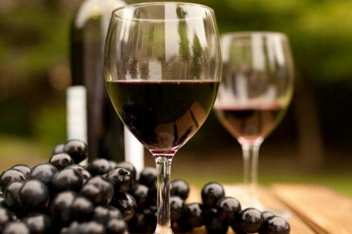 wineglass filled with wine with grapes in the background