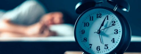 Alarm Clock with a man sleeping in the background Alarm Clock with a man sleeping in the background
