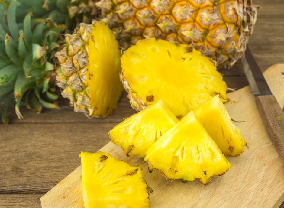 Pineapple on a cutting board with a knife.