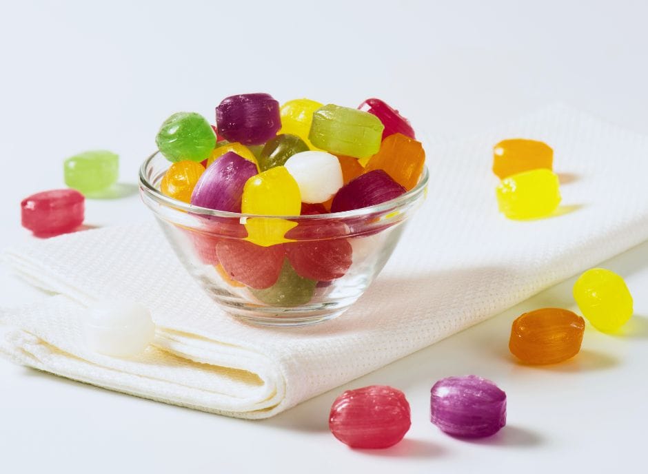 Colorful gummy bears in a glass bowl on a napkin.