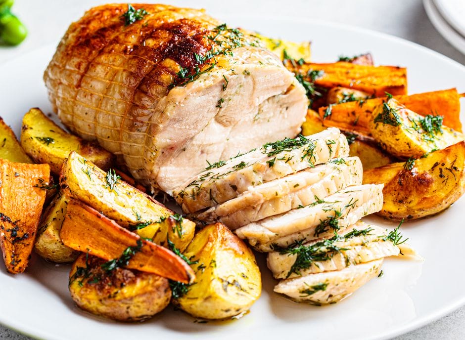 Roasted chicken with potatoes and herbs on a white plate.