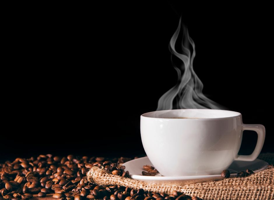 A cup of coffee with steam coming out of it on a black background.