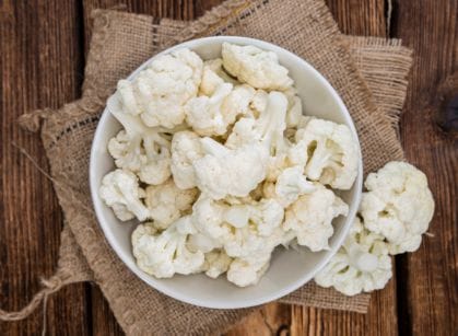 White cauliflower in a bowl on a wooden table.