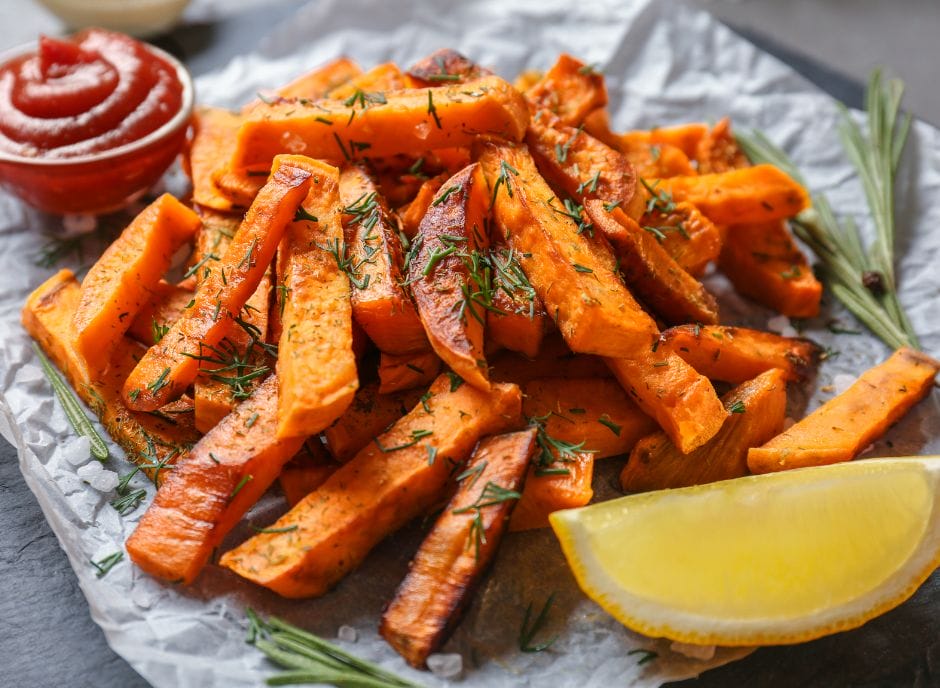 Sweet potato fries with dill and lemon wedges.