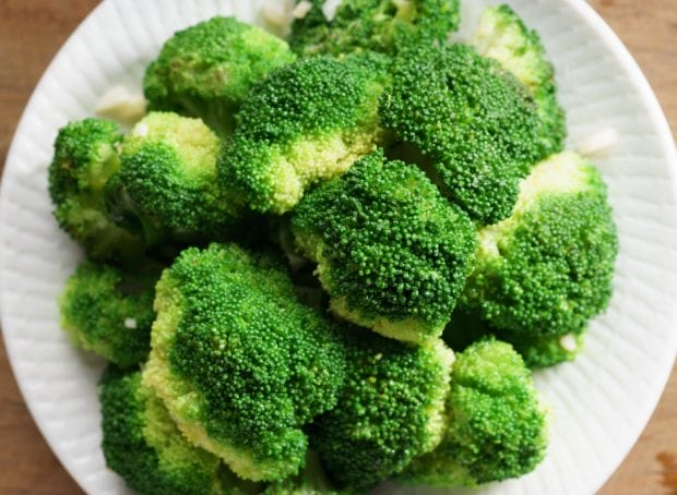 A plate of broccoli on a wooden table, suitable for a renal diet.