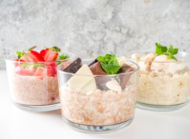Three glasses of oats with chocolate, strawberries, and mint.