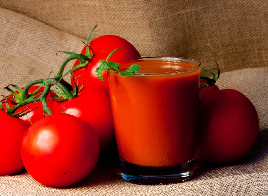 A glass of juice next to a bunch of tomatoes.
Keywords: tomato