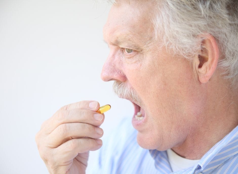 A man is taking a pill out of his mouth.