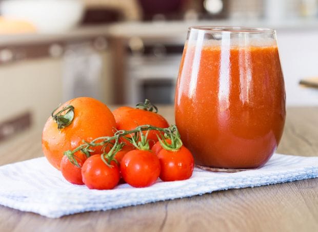 A glass of tomato juice and tomatoes on a kitchen towel, perfect for those with CKD.