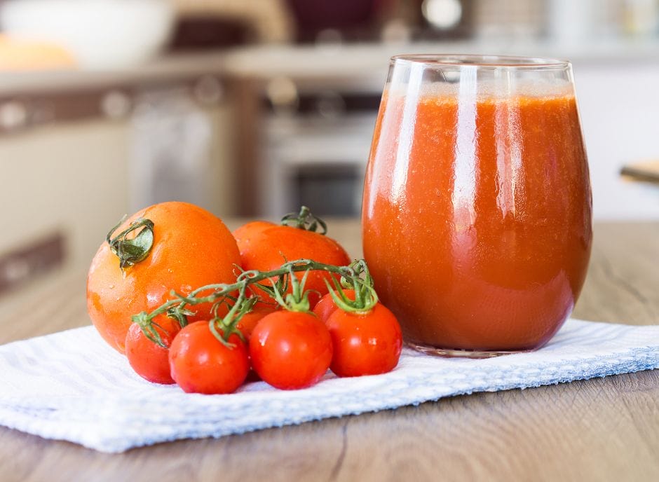 A glass of tomato juice and tomatoes on a kitchen towel, perfect for those with CKD.
