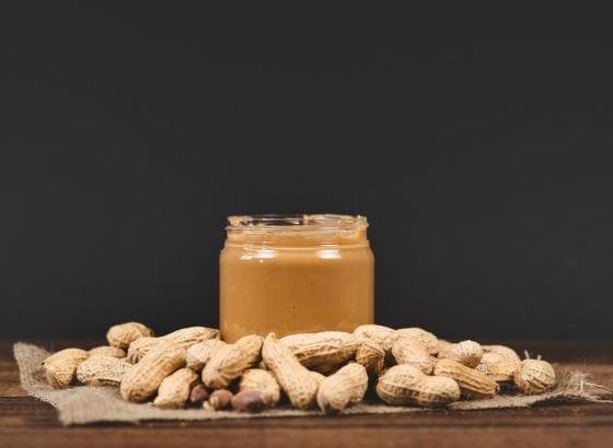 Peanut butter in a jar on a wooden table, suitable for a renal diet.