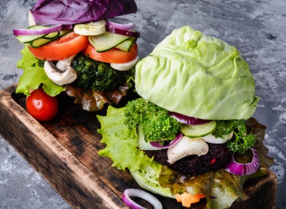 Two veggie burgers on a wooden board.