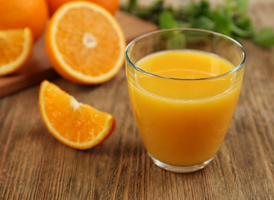 A glass of orange juice on a wooden table.