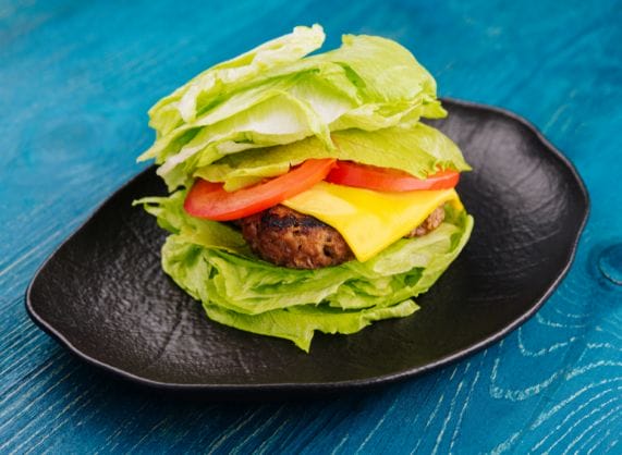 A hamburger with lettuce and tomatoes on a black plate.