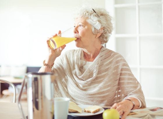 A woman drinking a glass of orange juice.