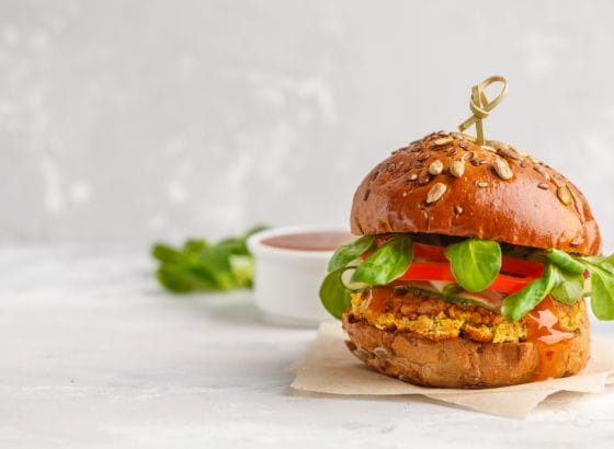 A burger with vegetables and sauce on a white background.