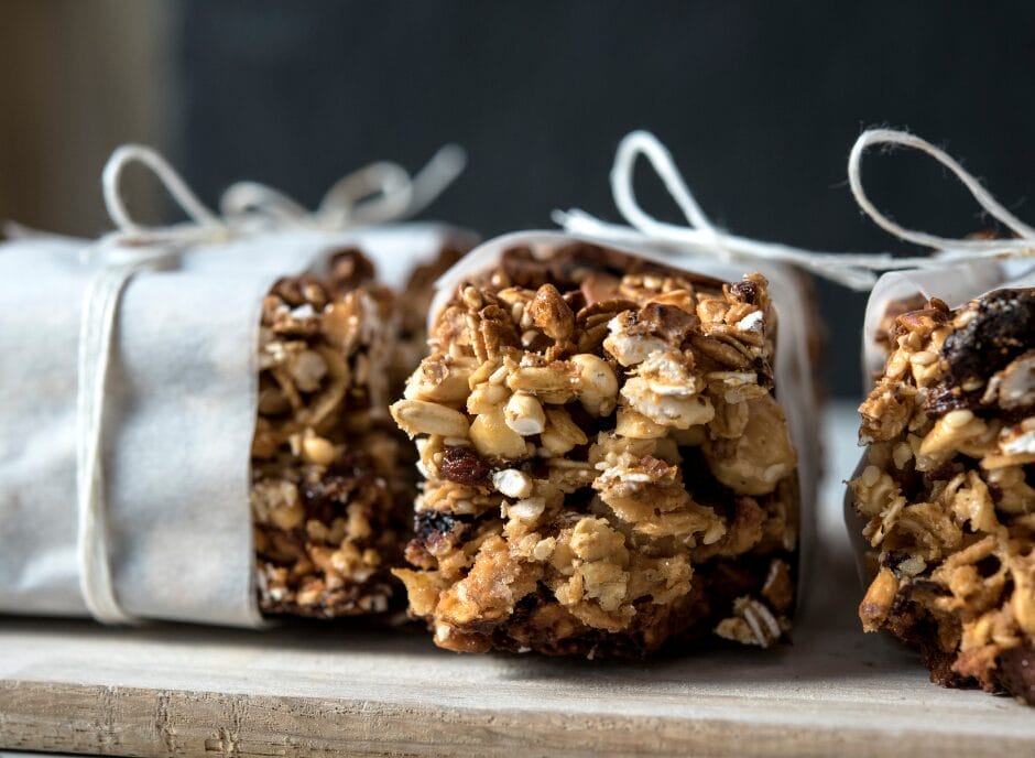 Granola bars wrapped in brown paper on a cutting board.