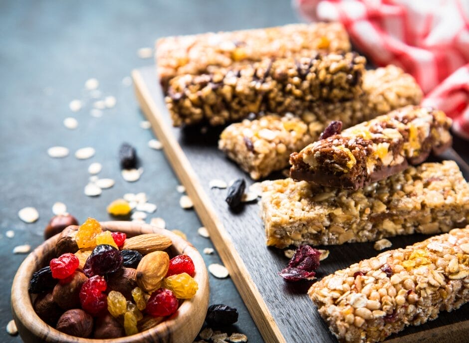 Granola bars with raisins and nuts on a wooden board.